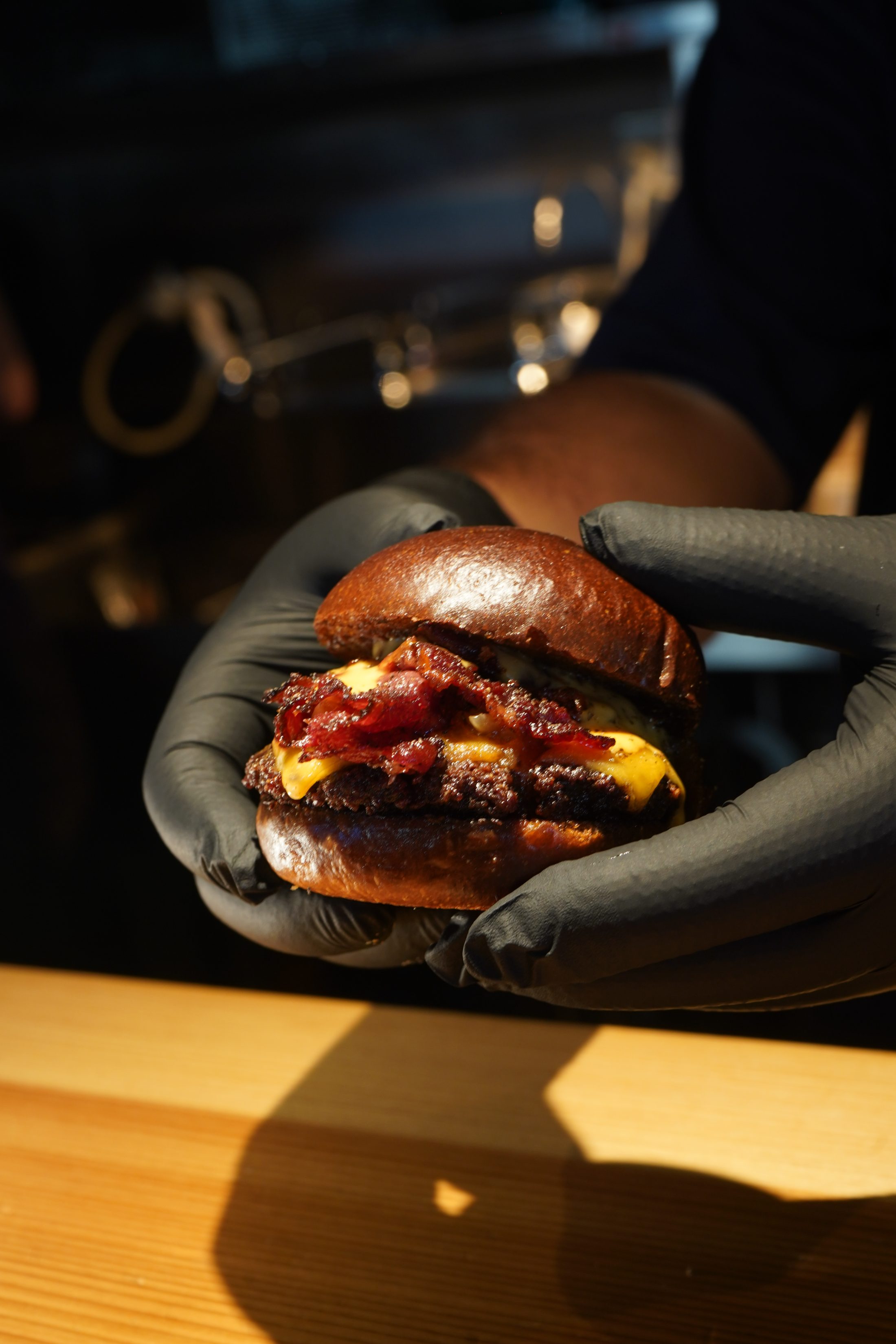 A wagyu cheeseburger held in gloved hands